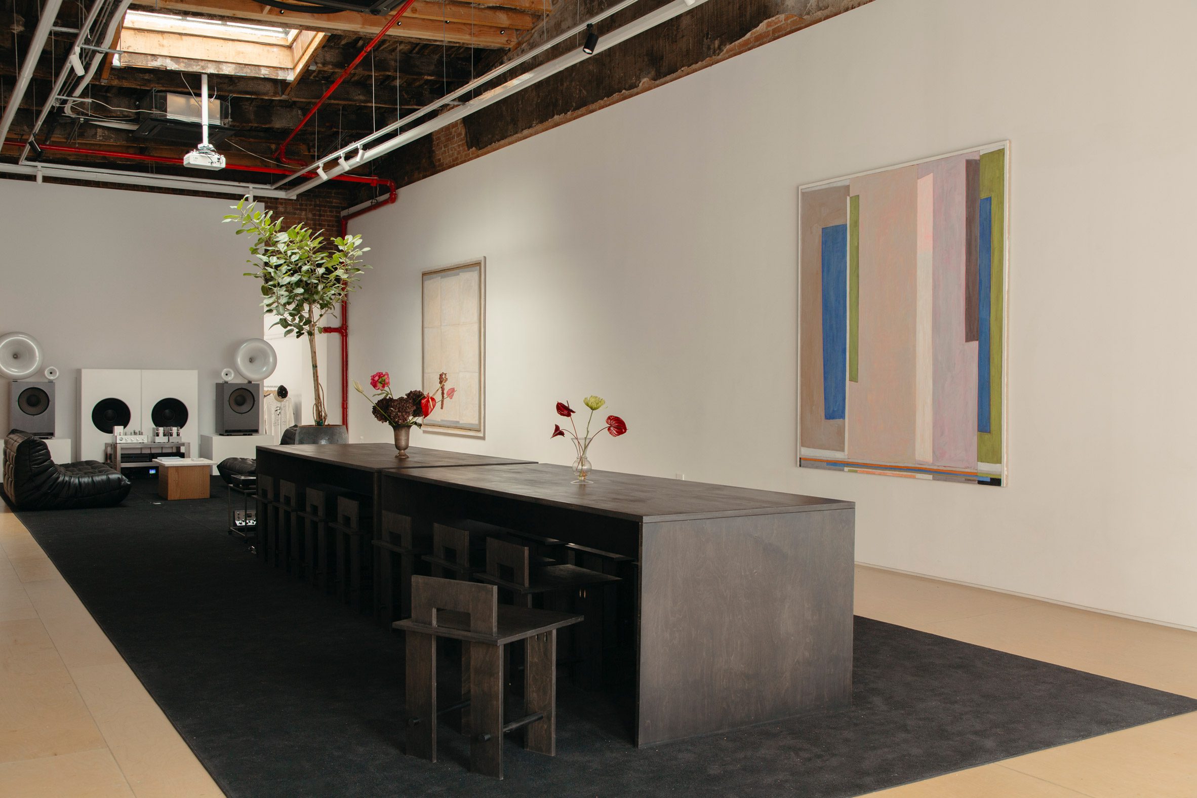 Loft gallery space set for the Silence Please dinner series, with a long communal table beneath hanging art.