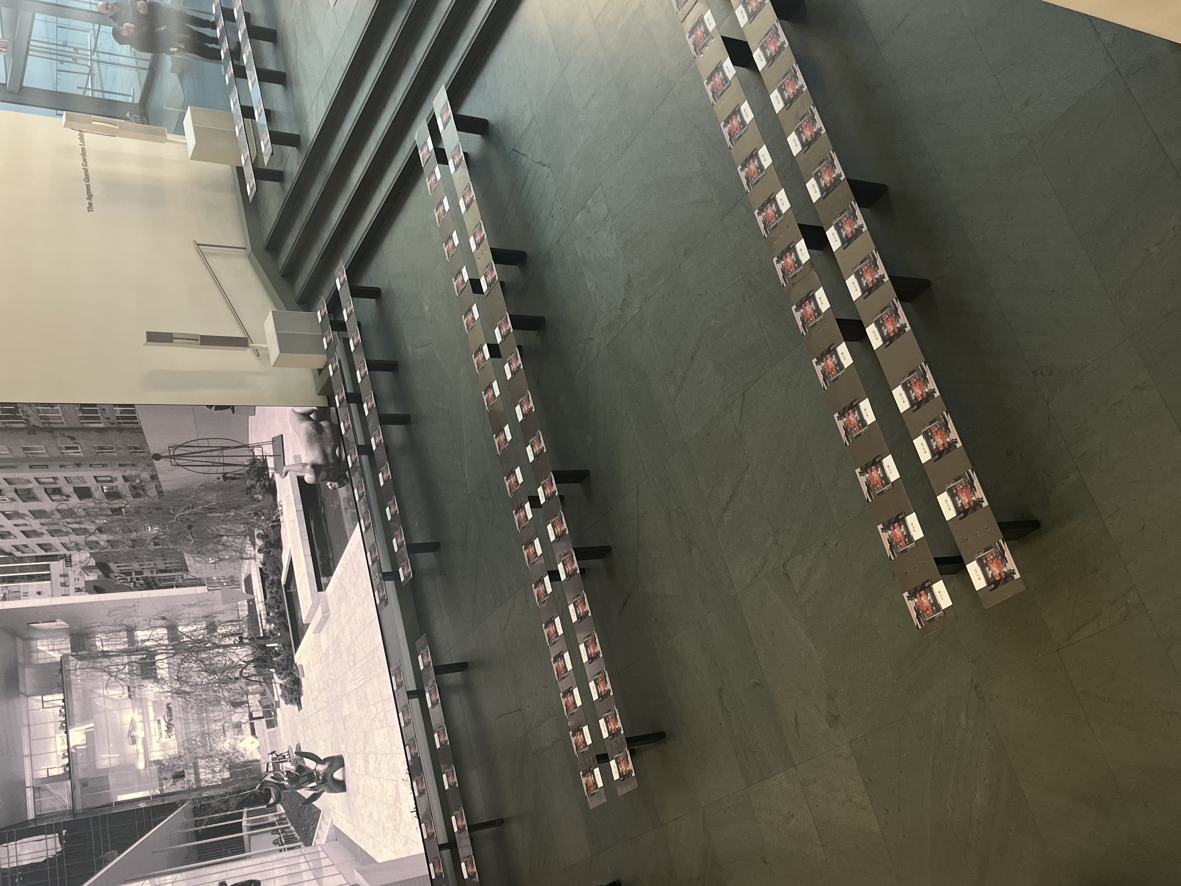 Rows of Tory Burch Fall/Winter 2026 seat cards laid out on empty benches in MoMA's lobby before doors open.